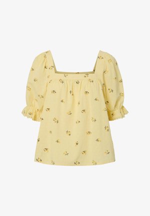 Blouse fleurie jaune en tissu texturé, avec décolleté carré et manches courtes bouffantes à volant. Petits motifs floraux visibles.