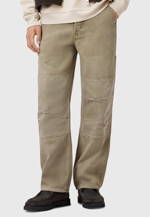 Beige cargo pants with a relaxed fit. Features distressed accents and patchwork details. Constructed from durable cotton blend material.