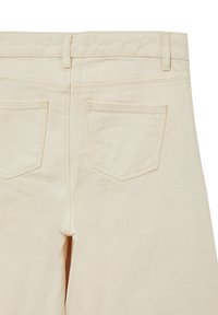 Pantaloni in denim beige visti da dietro, con due tasche posteriori, cuciture visibili e una consistenza liscia. Design a gamba dritta con vita media.