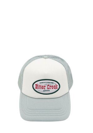 Svetlosivá a biela šiltovka s sieťovanou zadnou časťou a oválnou nášivkou s nápisom "Bitter Creek Wyoming" v červenom a čiernom texte.