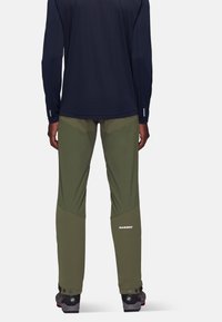 Groene wandelpantalons met een geometrisch ontwerp en een donkerblauwe shirt. Kenmerken zijn onder andere verstevigde panelen, verstelbare manchetten en logo-details.