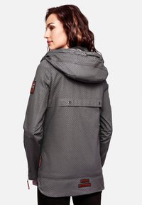 Gray waterproof jacket with a patterned texture, a hood, adjustable cuffs, and branded accents. Features a longer back hem for coverage.