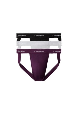 Trzy męskie jockstrapy Calvin Klein w kolorach czarnym, białym i ciemnofioletowym z markowymi paskami w pasie, ułożone pionowo na białym tle.