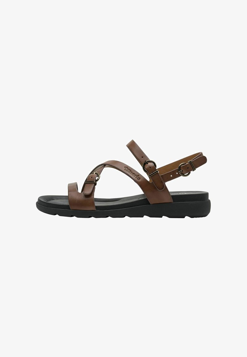 Sandale en cuir marron avec une semelle plate en caoutchouc noir, équipée de lanières croisées et de boucles réglables. Texture lisse et design minimaliste.