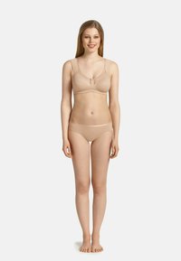 Soutien-gorge sans fil couleur chair et culotte assortie, fabriqués en tissu lisse avec des bretelles ajustables, présentant un fermoir central décoratif.