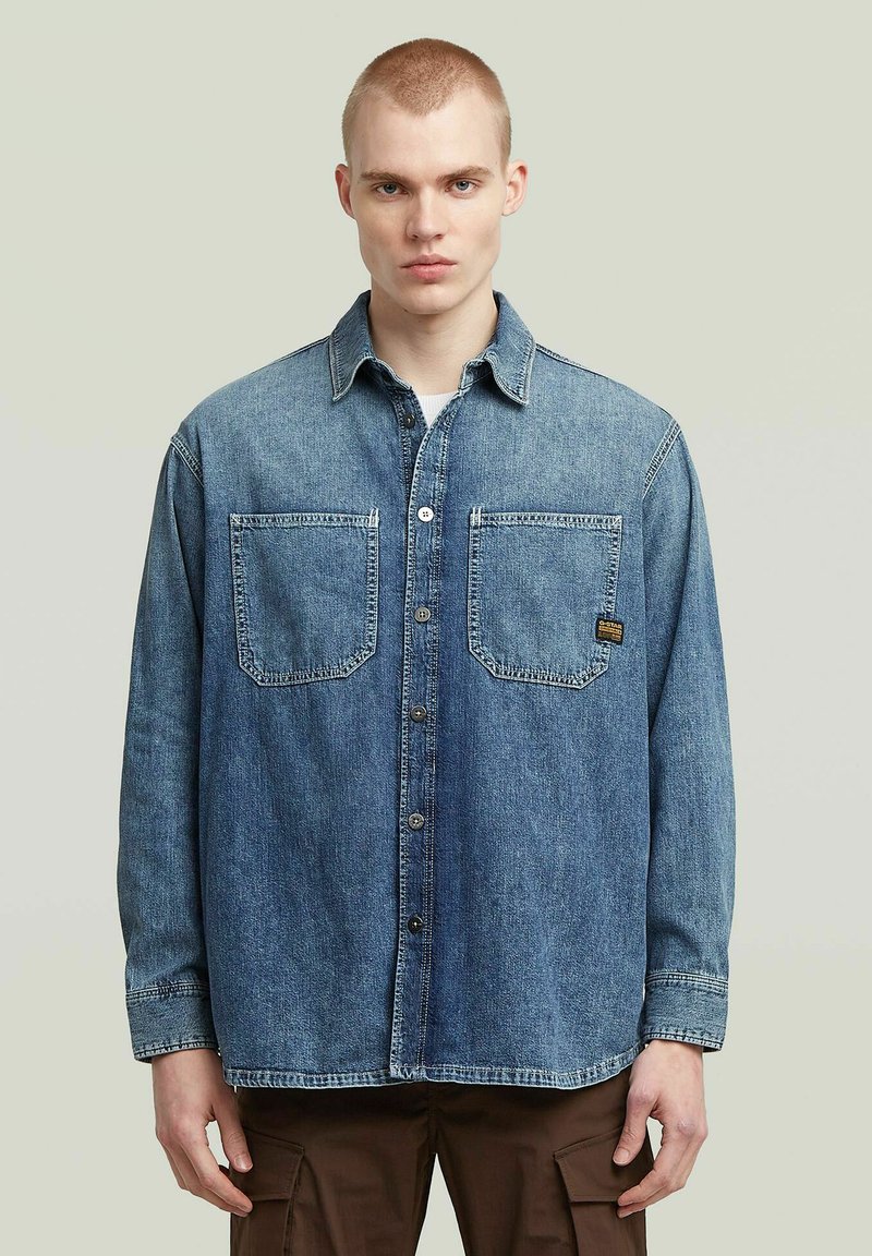 Jeansskjorta, ljusblå, med långa ärmar, spetsig krage och två bröstfickor. Avslappnad passform med knäppning och synliga sömmar.