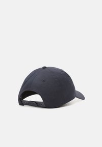 Casquette bleu marine en tissu texturé, avec une visière incurvée, une sangle ajustable à l'arrière, des trous de ventilation et un détail de logo subtil.