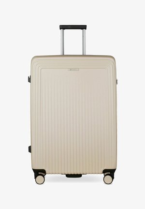 Grande valise rigide beige avec des rainures verticales, poignée noire étendue et quatre roulettes pivotantes noires et beiges sur fond blanc.
