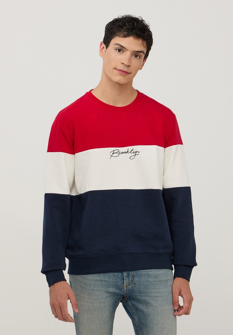 Felpa a blocchi di colore rosso, bianco e blu navy con collo rotondo, maniche lunghe e la scritta "Brooklyn" ricamata in corsivo sul petto.