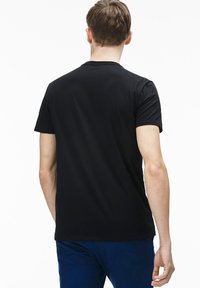 Camiseta negra de manga corta hecha de algodón suave, con un diseño limpio, un escote redondo y sin patrones ni elementos metálicos visibles.