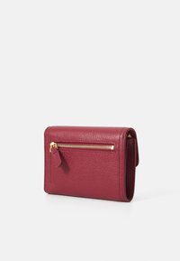 Compact burgundy leather wallet with a textured finish, featuring a gold zipper and a small pull tab on the exterior for easy access.