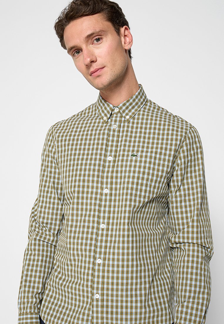 Grün- und blau kariertes Hemd mit Kragen, ausgestattet mit weißen Knöpfen und einem kleinen gestickten Logo auf der linken Brust.