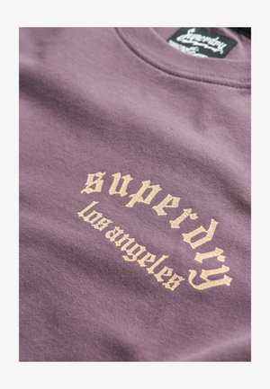 Lilla sweatshirt med en struktureret, cremefarvet grafik, der står "superdry los angeles," med rund halsudskæring og blødt stof.