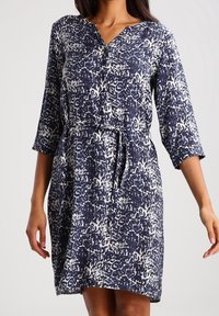 Marineblaues und weißes gemustertes Kleid mit V-Ausschnitt, 3/4-Ärmeln und gebundenem Taillenzug. Hergestellt aus leichtem Stoff mit lockerer Passform.