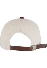 Beige kasket med justerbar brun læderrem, rund krone og maroon knapdetalje. Blødt stof, designet til afslappet brug.