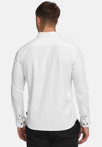 Weißes Langarmhemd mit Button-Down-Kragen. Verfügt über dunkle Knöpfe an den Manschetten und eine taillierte Passform, hergestellt aus glattem Stoff.