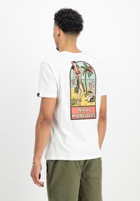 Hvid bomulds t-shirt med et farverigt grafisk design på ryggen, der viser en kvinde, palmer og teksten "NAVAL MANEUVERS." Korte ærmer.
