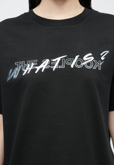 T-shirt preta de algodão com texto refletor em branco e prata, com um corte casual e decote redondo. O texto diz: "WHAT IS?" e "THE KOOPLES?"