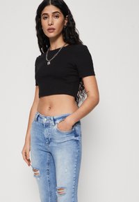 Black cropped t-shirt with short sleeves paired with light blue distressed jeans featuring rips at the knees and a classic five-pocket design.