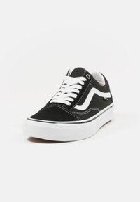 Las zapatillas negras de ante tienen una suela de goma blanca, cordones blancos y un destacado diseño Swoosh blanco. La costura es visible a lo largo de los bordes.