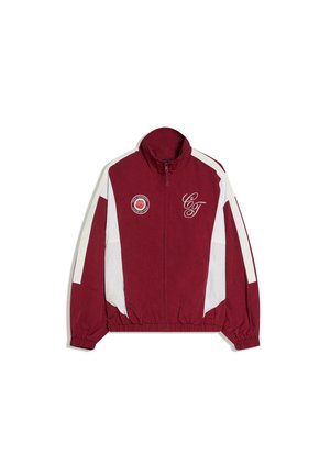 Bordó és fehér cipzáras dzseki rugalmas mandzsettákkal, magas gallérral, "C&T" felirattal a mellkasnál, és egy kör alakú, rózsát ábrázoló logóval a bal oldalon.