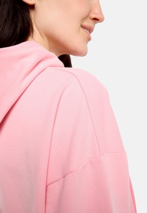 Pinkfarbener Hoodie mit weicher Textur, oversized Design und großer Kapuze. Sichtbare Nahtdetails und überschnittene Schultern sorgen für eine entspannte Passform.