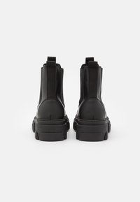 Černé kotníkové boty s robustní platformou. Vyrobené z hladké kůže, s elastickými bočními panely a dvěma poutky na zadní straně.