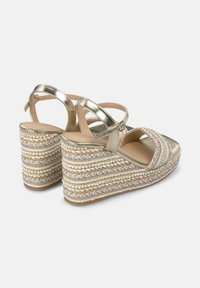 Gouden metallic wedge sandalen met een geweven strohakken, voorzien van ingewikkelde kralenaccenten en kruisbanden voor een stevige pasvorm.