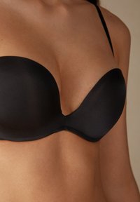 Zwarte gevoerde strapless beha met een gladde textuur, met een diepe decolleté en gemolde cups, ontworpen voor een naadloze pasvorm.