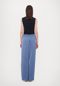 Top senza maniche di colore navy abbinato a pantaloni larghi leggeri di colore azzurro con vita elastica. Tessuto morbido con un design minimal.