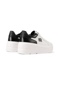 Sneaker bianchi con tacco texturizzato nero, suola piatta e accento con logo. Presentano una finitura liscia e un design con lacci.