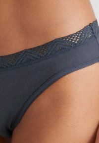 Culotte en coton gris foncé avec une taille en dentelle à motif zigzag. Texture lisse avec une coupe ajustée.