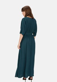 Teal maxi-jurk met een losse pasvorm, korte mouwen en een strakke taille. Beschikt over een vloeiende silhouet en een gestructureerde stof.