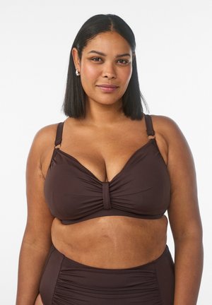 Woman with medium skin tone and black shoulder-length hair wearing a dark brown bikini top and matching high-waisted bottoms, smiling gently.