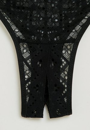 String noir en dentelle avec un motif floral, détail découpé à l'arrière et taille élastique. Texturé avec un travail de dentelle complexe.