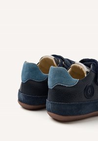 Sneaker in pelle blu navy con tacco in suede texturizzato e accenti azzurri. Include dettaglio del logo circolare e una morbida fodera interna. Suola in gomma marrone.