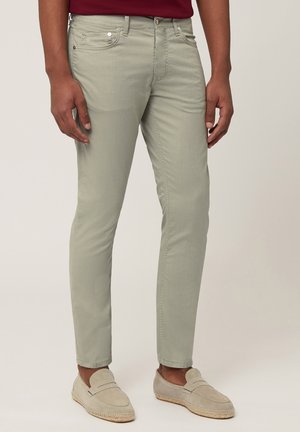 Lichtgroene slim-fit broek van lichtgewicht stof, met een rits en vijf zakken, en subtiele stiksels. Gecombineerd met beige instappers.