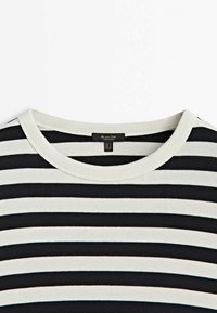 Mustat ja valkoiset vaaka-raidalliset ympäri kaulusta oleva paita, jossa on kangaslabeli kaula-aukossa näyttäen koon ja brändin tiedot.