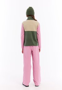 Fleece jack in het roze, groen en beige met een hoge kraag; gecombineerd met losse roze broek; zachte textuur, casual ontwerp en minimale details.