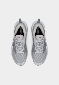 Ζευγάρι αθλητικά παπούτσια σε γκρι και λευκό με κορδόνια, πλεκτό επάνω μέρος και επενδύσεις με λογότυπο, σε λευκό φόντο.