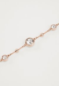 Pulseira de corrente em ouro rosé com três cristais transparentes redondos fixados em fechos de metal, intercalados com pequenas contas de metal, criando um design delicado.
