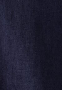 Texture en tissu tissé bleu foncé avec des fils fins visibles et des variations subtiles de couleur et de motif de tissage.