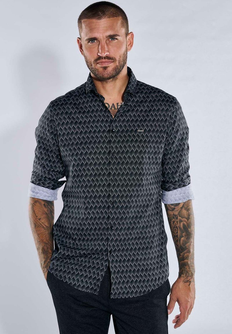 Black patterned shirt with textured diamond design, structured collar, and button-down front. Cuffed sleeves reveal a lighter inner fabric.