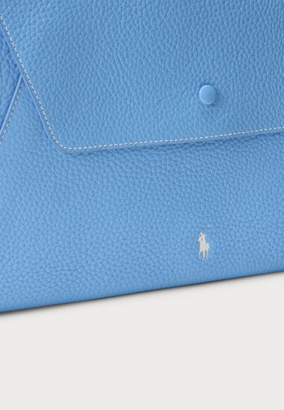 Lys blå lærveske med teksturert overflate, med klaffelukking og en sentral knapp. Inkluderer et hvitt logoaksent.