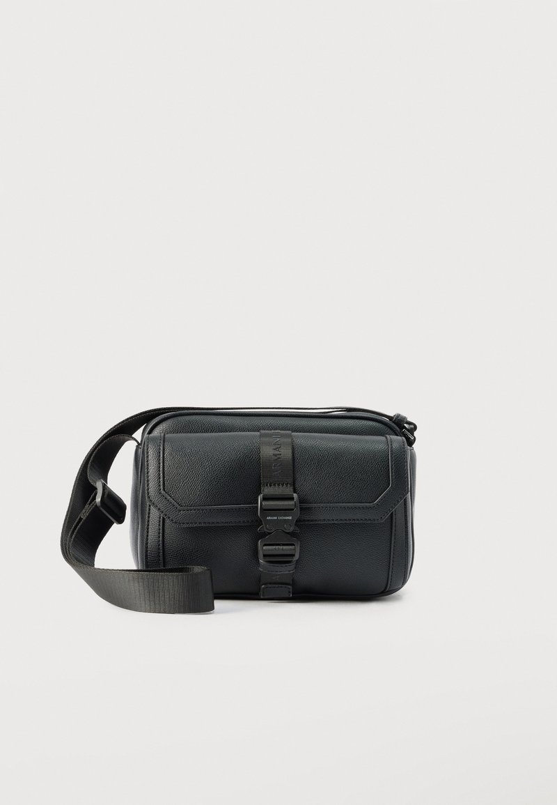 Μαύρη τσάντα χιαστί με υφή, ρυθμιζόμενο λουρί και εμπρόσθιο καπάκι που ασφαλίζει με πλαστική αγκράφα με ανάγλυφη επωνυμία.