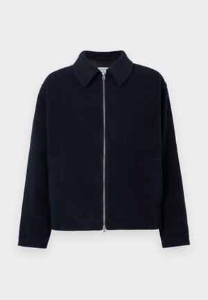 Jachetă zip-up de culoare albastră închisă, confecționată dintr-un material texturat. Prezintă un guler și două buzunare laterale. Design simplu și structurat.