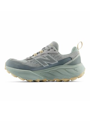 Gray and beige New Balance sports shoe with thick sole, mesh and suede upper, padded collar, and lace-up front, shown in profile view.