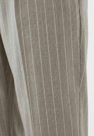 Nærbilde av grå bukser i stoff med tynne hvite vertikale nålestriper og detalj ved sidesømmen.