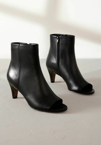 Mustad musta nahast ankle boots avatud varvastega, kitsaste kontsadega ja külglahtise tõmblukuga. Sile tekstuur ja minimalistlik disain puhaste joontega.