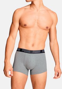 Graue Baumwoll-Boxershorts mit einem schwarzen Bund, der das "PUMA"-Logo trägt. Das Design ist eng anliegend mit einer weichen Textur und hat eine Länge bis zur Mitte des Oberschenkels.